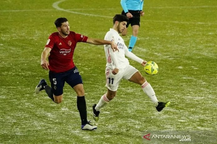 Pemain sayap Real Madrid Marco Asensio (putih) berusaha menggiring bola melewati kawalan bek Osasuna David Garcia dalam lanjutan Liga Spanyol di Stadion El Sadar, Pamplona, Spanyol, Sabtu (9/1/2021) waktu setempat. (ANTARA/REUTERS/Vincent West)