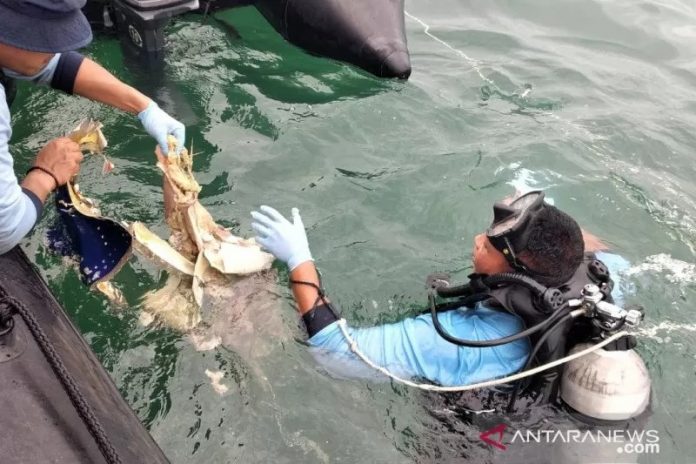 Tim penyelam dari Satuan Komando Pasukan Katak (Kopaska) TNI Angkatan Laut mengevakuasi serpihan pesawat yang ditemukan dalam pencarian pesawat Sriwijaya PK-CLC SJ182, yang jatuh di perairan Kepulauan Seribu, Minggu (10/1/2021). (ANTARA/Fauzi Lamboka)