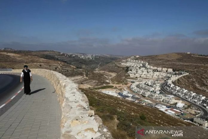 Seorang wanita berjalan dengan latar gedung pemukiman Israel di sekitar Givat Zeev dan Ramat Givat Zeev di wilayah pendudukan Israel, Tepi Barat, dekat Yerusalem, Selasa (30/6/2020). ANTARA FOTO/REUTERS/Ammar Awad/hp/djo