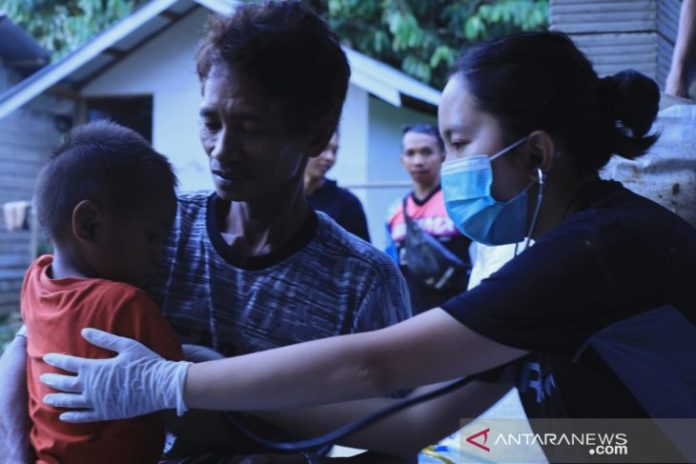 Dokter umum, Monika Astria Putagalong saat memeriksa anak warga Dusun Rantau Perupuk, Desa Datar Ajab yang digendung Ayahnya karena sakit pilek. Sabtu, 23/1/2021 (Antaranews Kalsel/Muhammad Fauzi Fadilah)