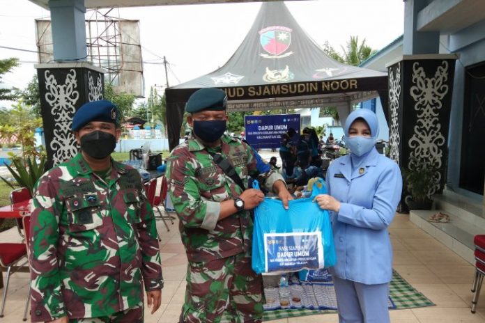 Ketua PIA Ardhya Garini Cabang 11/D II, Rosa Taufiq Arasj, menyerahkan secara simbolis makanan siap saji kepada personel TNI untuk didistribusikan kepada korban banjir, disaksikan Komandan Lanud Sjamsudin Noor Banjarmasin, Kolonel Pnb M Taufiq Arasj (kiri). Makanan siap saji tersebut disediakan oleh Dapur Umum SMA Pradita Dirgantara. (Foto Yose Rizal/Antaranews Kalsel)