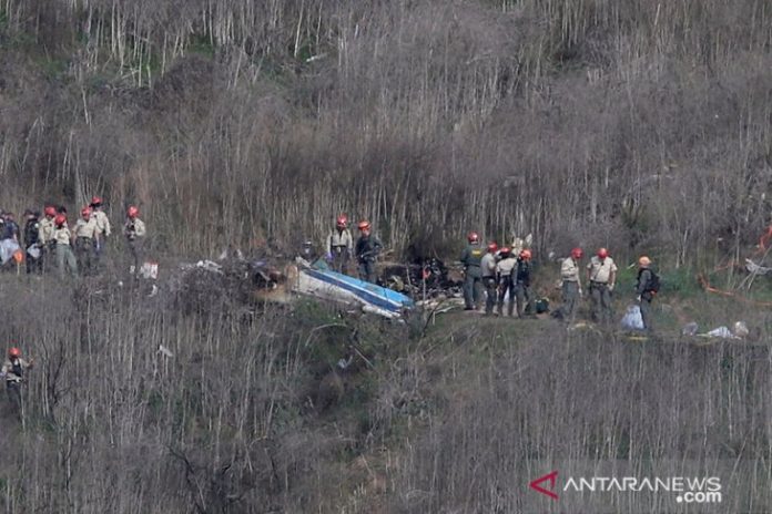 Petugas dan polisi bekerja di lokasi jatuhnya helikopter yang membawa pemain basket NBA Kobe Bryant saat penyelidikan terus berlanjut di Calabasa, California, Amerikat Serikat, Senin (27/1/2020). REUTERS/Danny Moloshok/aww/cfo (REUTERS/DANNY MOLOSHOK)