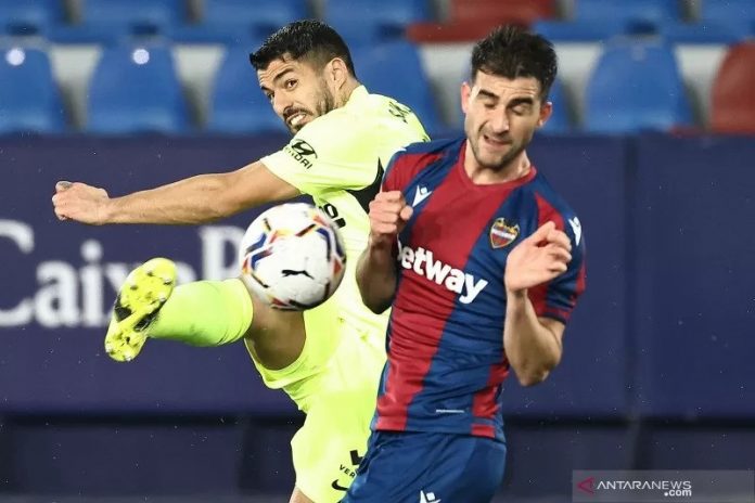 Penyerang Atletico Madrid, Luis Suarez (kuning) menendang bola melewati bek Lavante, Sergio Postigo. (AFP via antara)