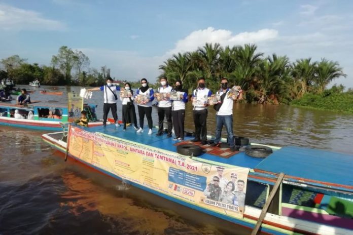 Anggota Biro SDM Polda Kalsel membagikan brosur penerimaan anggota Polri di kawasan Pasar Terapung Lokbaintan. (antara)