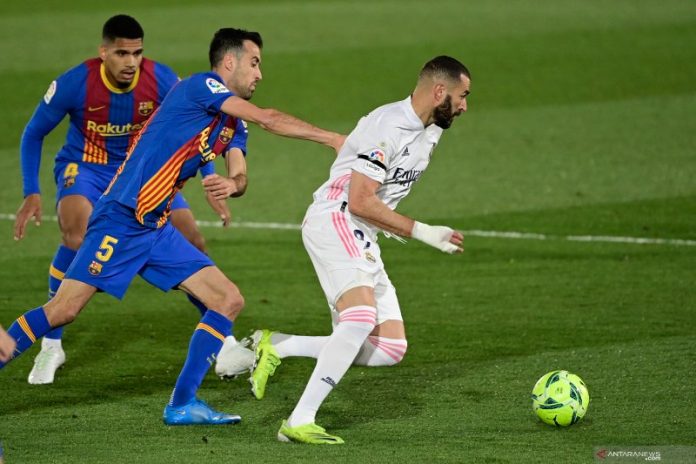 Penyerang Real Madrid, Karim Benzema (kanan) berusaha melepaskan diri dari kawalan dua pemain Barcelona Sergio Busquet dan Ronald Araujo dalam pertandingan Liga Spanyol d iAlfredo di Stefano pada 11 April 2021.(AFP/JAVIER SORIANO)