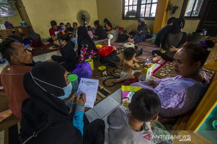 Seorang petugas mendata warga korban banjir berada di Posko Pengungsian korban banjir di Gedung Majelis Ta'lim Desa Sungai Danau, Kabupaten Tanah Bumbu, Kalimantan Selatan, Sabtu (15/5/2021).