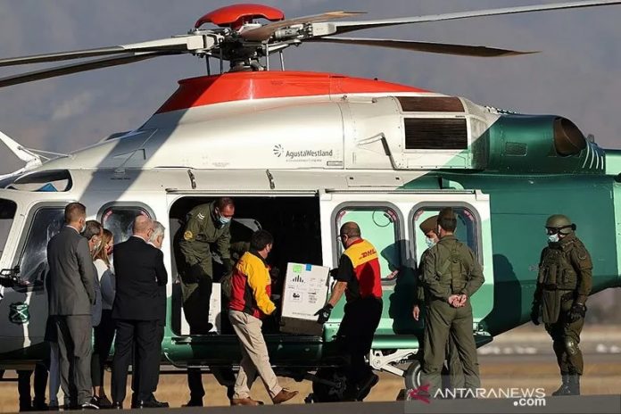 Presiden Chile Sebastian Pinera melihat ke arah pekerja yang membawa kotak vaksin Pfizer-BioNTech COVID-19 ke helikopter, di Bandara Internasional Santiago, Chile, Kamis (31/12/2020). ANTARA FOTO/REUTERS/Ivan Alvarado/pras/cfo/aa.