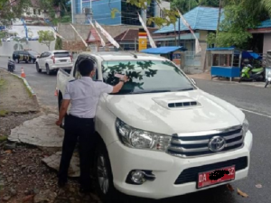 Petugas Dishub Kotabaru memasang stiker di sebuah mobil dinas yang parkir sembarangan. (Istimewa)