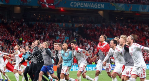 Para pemain dan staf Denmark merayakan keberhasilan mereka yang secara dramatis lolos ke 16 besar Euro 2020 setelah menjadi runner up usai mengalahkan Rusia 4-1 di Parken Stadium, Copenhagen, Denmark, 21 Juni 2021, dan "dibantu" oleh kemenangan 2-0 Belgia atas Finlandia dalam pertandingan lain Grup B. Belgia memuncaki grup ini dengan sembilan poin. (Pool via REUTERS/Wolfgang Rattay) (REUTERS)