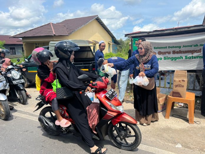 Relawan Saraba Kawa PAM Bandarmasih membagikan paket roti dan buah kepada pengendara jemaah haul ke-20 Guru Sekumpul, Minggu. (wartabanjar.com - Iqnatius Aprianus)