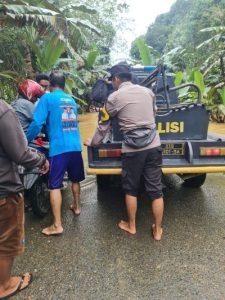 Personel Polsek Muara Uya membantu warga melintasi genangan banjir. (wartabanjar.com - Ist. Humas Polres Tabalong)