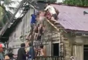 Warga menurunkan tubuh Adang dari atas atap setelah tersengkat aliran listrik di Kinrtap, Kabupaten Tanah Laut. (wartabanjar.com - Istimewa)