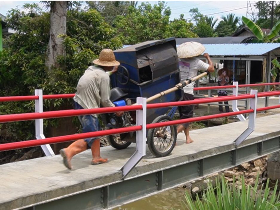 Warga memanfaatkan Jembatan Garuda untuk mengangkut mesin padi